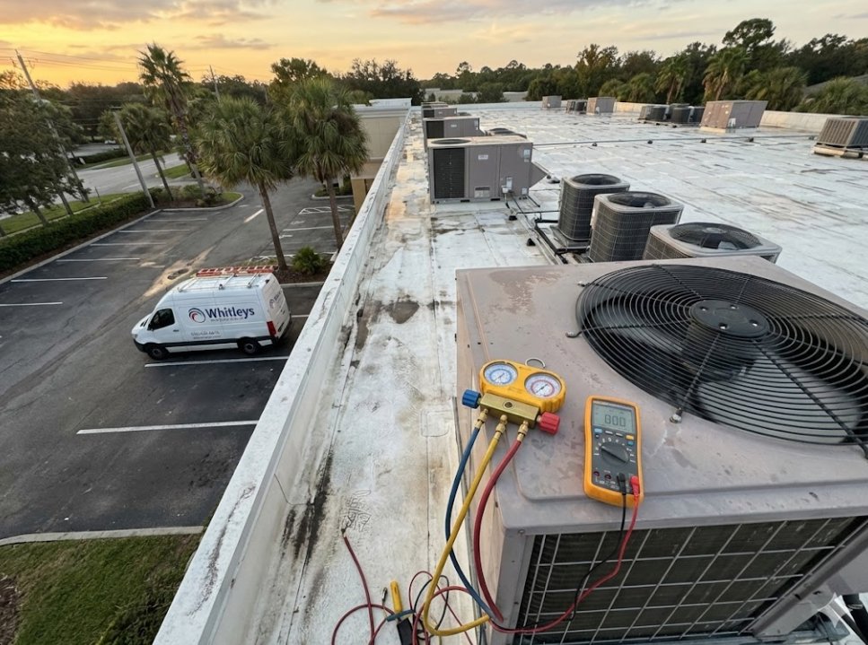 An HVAC technician's tools connected to a commercial AC unit on a rooftop, indicating diagnostic work by Whitleys Heating and Air in Jacksonville, FL.