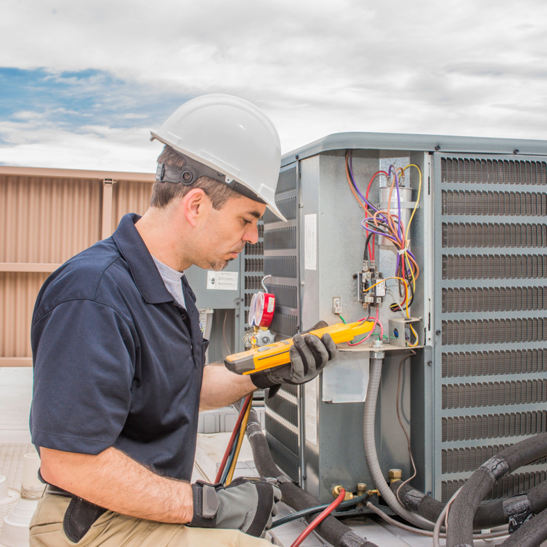 An HVAC technician from Polar Aire Heating & Cooling diagnosing a commercial rooftop unit in Olathe, KS