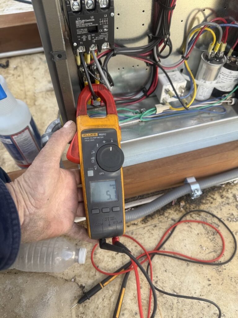 An HVAC technician using a clamp meter to diagnose an electrical panel on an HVAC unit for Four Corners Service Co. in Farmington, NM.