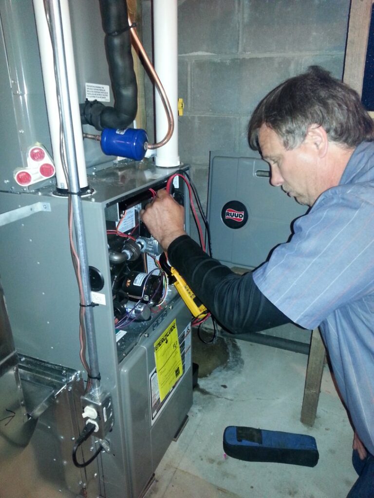 An Action Mechanical LLC technician diagnosing a furnace or air handler with a multimeter in Eau Claire, WI.
