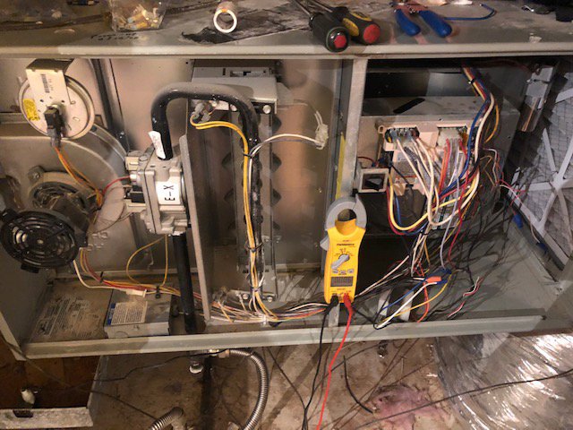 HVAC technician diagnosing an open furnace or air handler unit with a multimeter by Climate Care Heating & Air Conditioning in Norwalk, CT