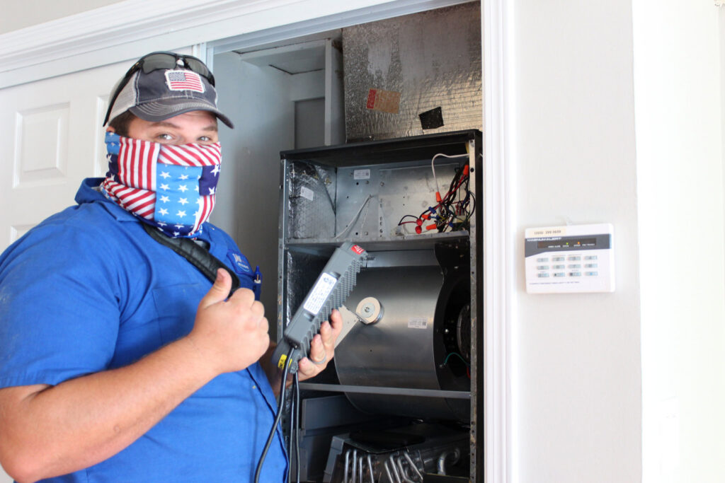 An HVAC technician diagnosing an indoor air handler unit for J&W Heating and Air + Plumbing in Jacksonville, FL.