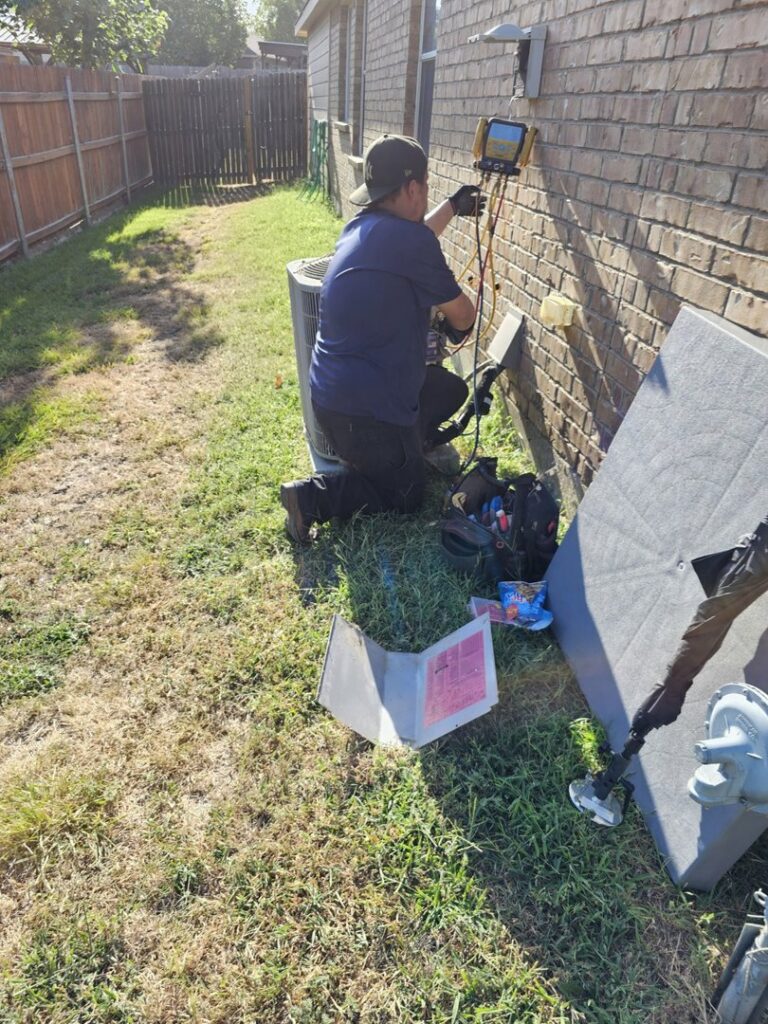 An HVAC technician kneeling and diagnosing an outdoor AC unit with a tool for MasterCraft Mechanical, LLC. in Haslet, TX.