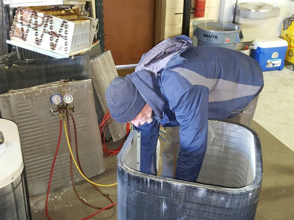 An Air Specialty Heating & Air Conditioning technician diagnosing an outdoor HVAC unit with gauges in Norfolk, VA.