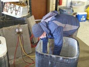An Air Specialty Heating & Air Conditioning technician diagnosing an outdoor HVAC unit with gauges in Norfolk, VA.