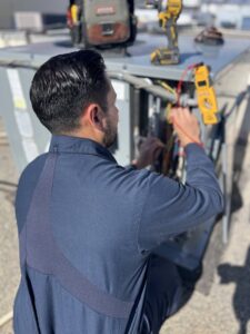 An Instant Air HVAC technician diagnosing an outdoor unit with a multimeter in Las Vegas, NV.