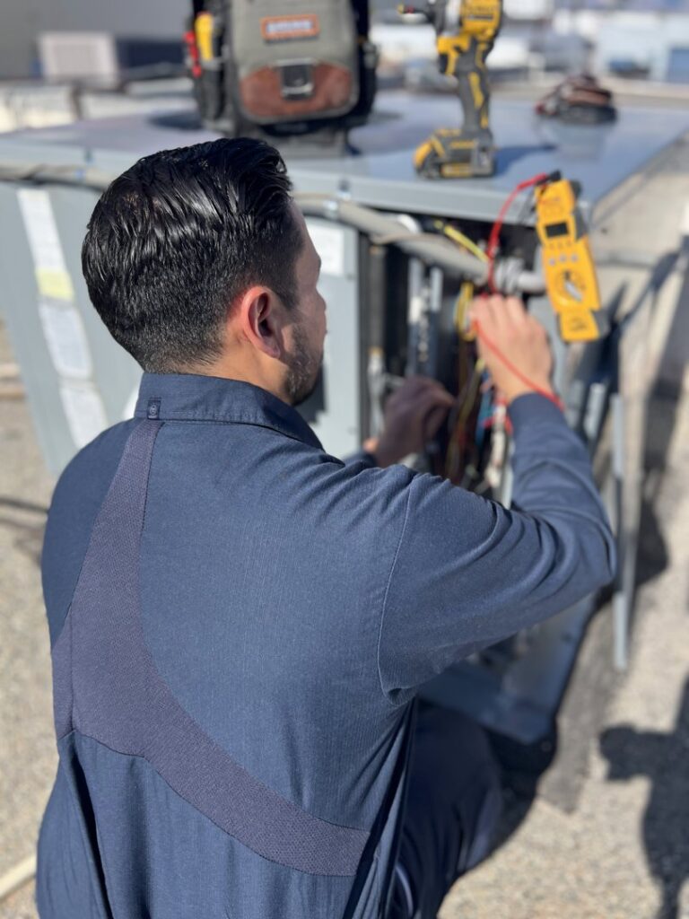 An Instant Air HVAC technician diagnosing an outdoor unit with a multimeter in Las Vegas, NV.