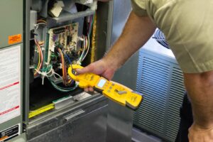 An HVAC technician from Nortek Environmental, Inc. using a multimeter to diagnose an HVAC unit in Naperville, IL.