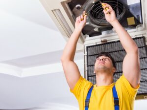 An HVAC technician using a drill to repair an indoor AC unit for ChillTek AC Repair Glendale in Glendale, AZ.