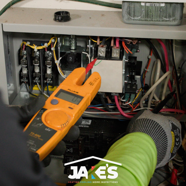 An HVAC technician performing electrical diagnostics on a control panel with a multimeter for Jake's Heating and Cooling in Buffalo, NY.