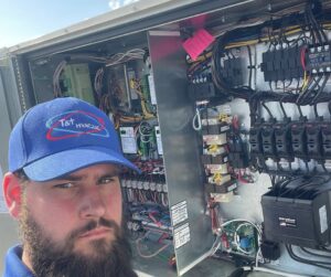 An HVAC technician from T & T HVAC working on the complex electrical control panel of a large unit in Amherst, OH.