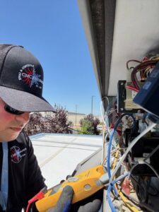 An HVAC technician performing electrical repair on a rooftop unit for CMC Mechanical, LLC in Caldwell, ID.