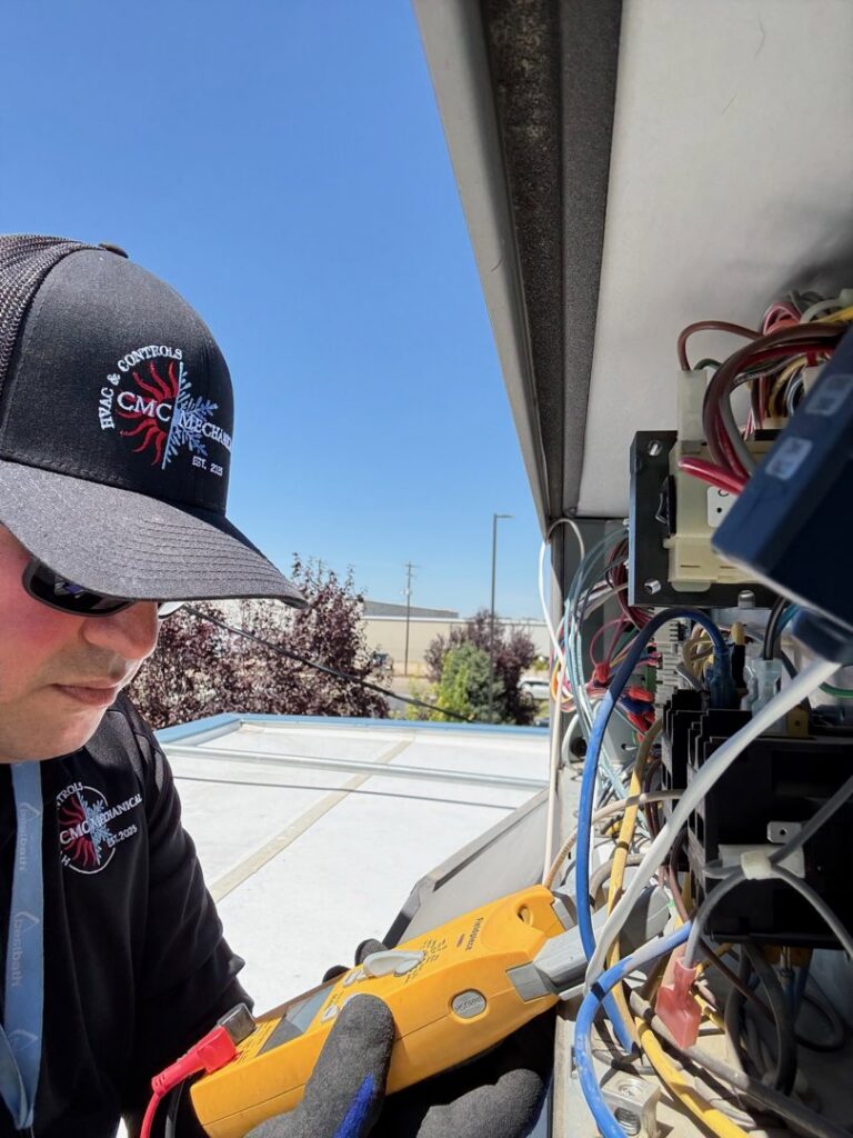 An HVAC technician performing electrical repair on a rooftop unit for CMC Mechanical, LLC in Caldwell, ID.