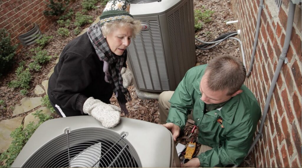 A Berico HVAC technician explaining service details to a customer next to an outdoor air conditioning unit in Greensboro, NC