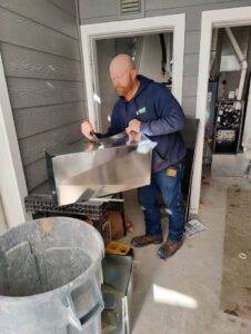 An HVAC technician from Greens Heating & Air Conditioning fabricating sheet metal ductwork in Douglasville, GA.