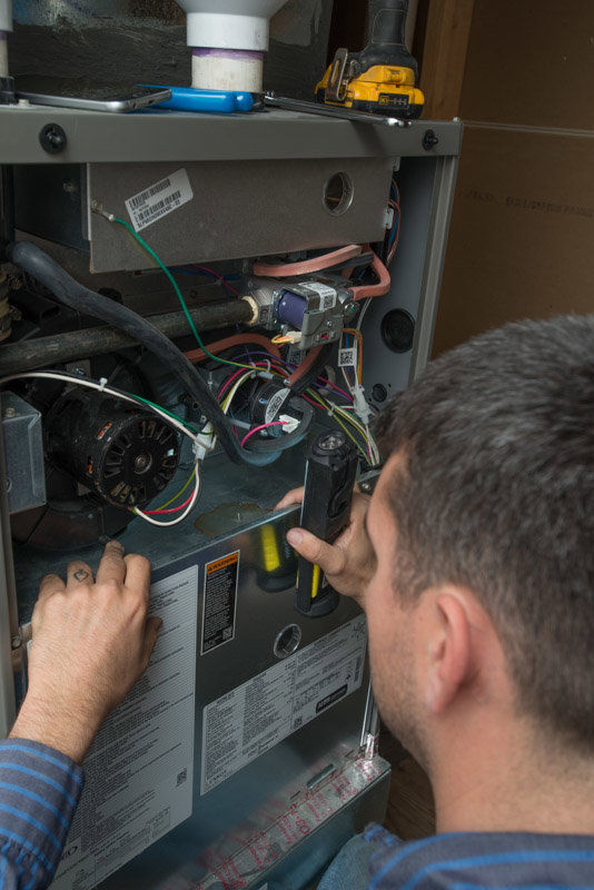An HVAC technician performing a furnace repair or inspection for Reliable Heating & Cooling LLC in Colorado Springs, CO