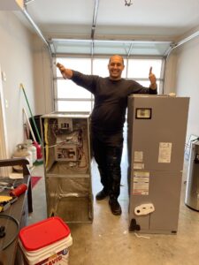 An HVAC technician from KMC Heating and Cooling LLC standing next to a new furnace installation in Clarksville, TN.