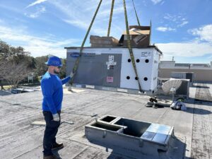 An Air Zero HVAC technician guiding a large commercial unit during a rooftop installation in Largo, FL