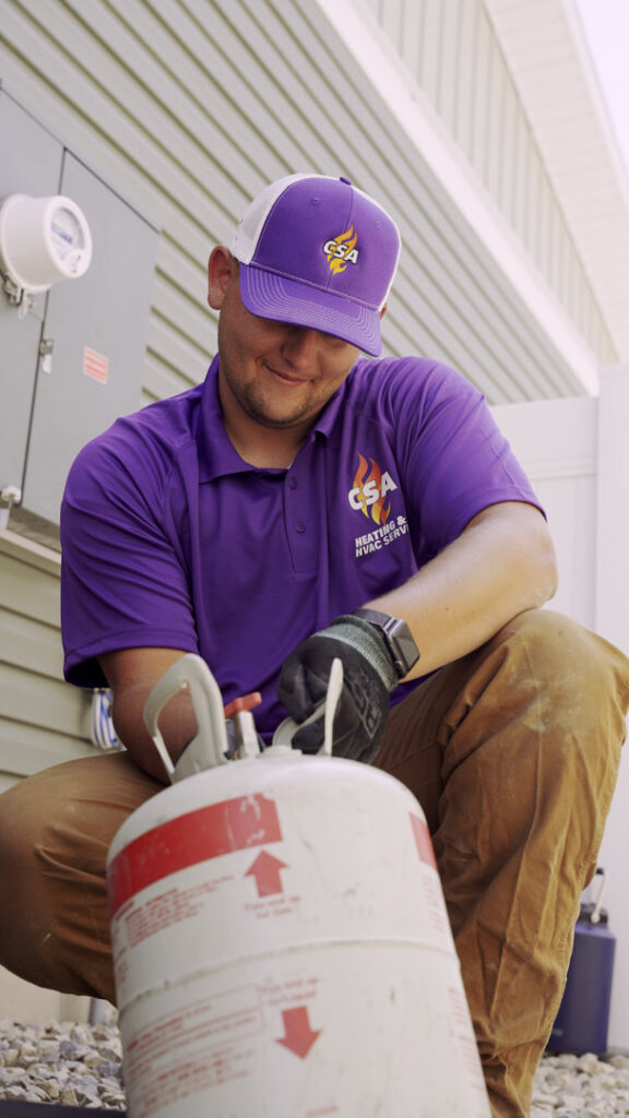 An HVAC technician from CSA HVAC Services handling a refrigerant tank during AC service in Orem, UT.
