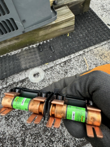 An HVAC technician's gloved hand holding electrical fuses during a repair job by 511Comfort, LLC in Nashville, TN.