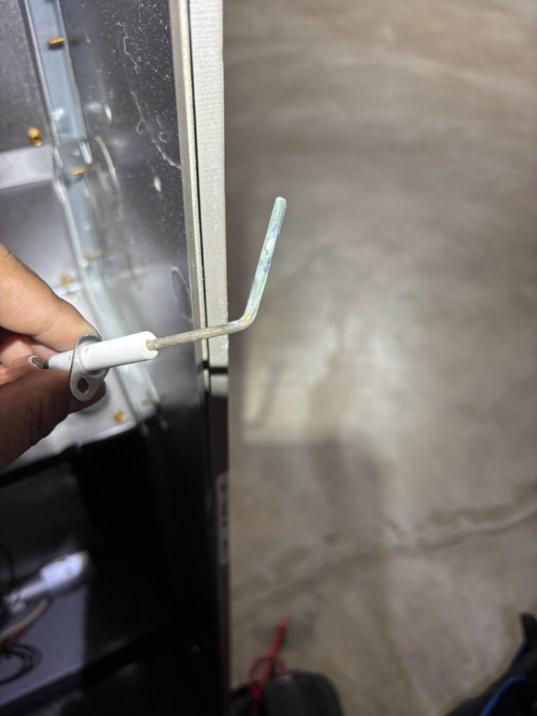 An HVAC technician holding a furnace igniter during a service call for Cool y Caliente HVAC Services in Bonner Springs, KS.