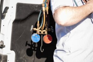An HVAC technician from DFH Company Heating and Air Conditioning holding manifold gauges, ready for service in Louisville, KY.