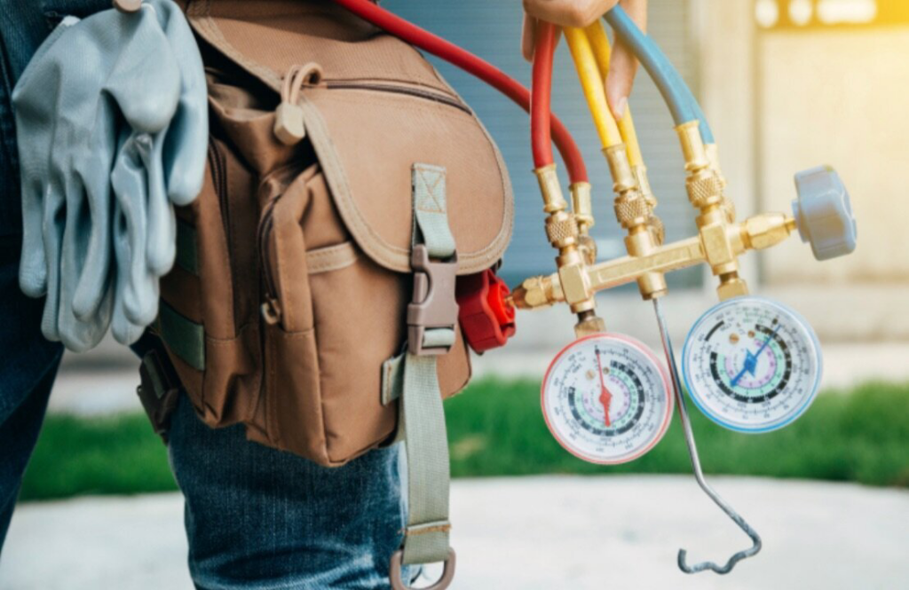 An HVAC technician holding manifold gauges and wearing a tool belt for HVAC Erie in Erie, PA.