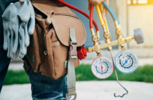 An HVAC technician holding manifold gauges and wearing a tool belt for HVAC Erie in Erie, PA.