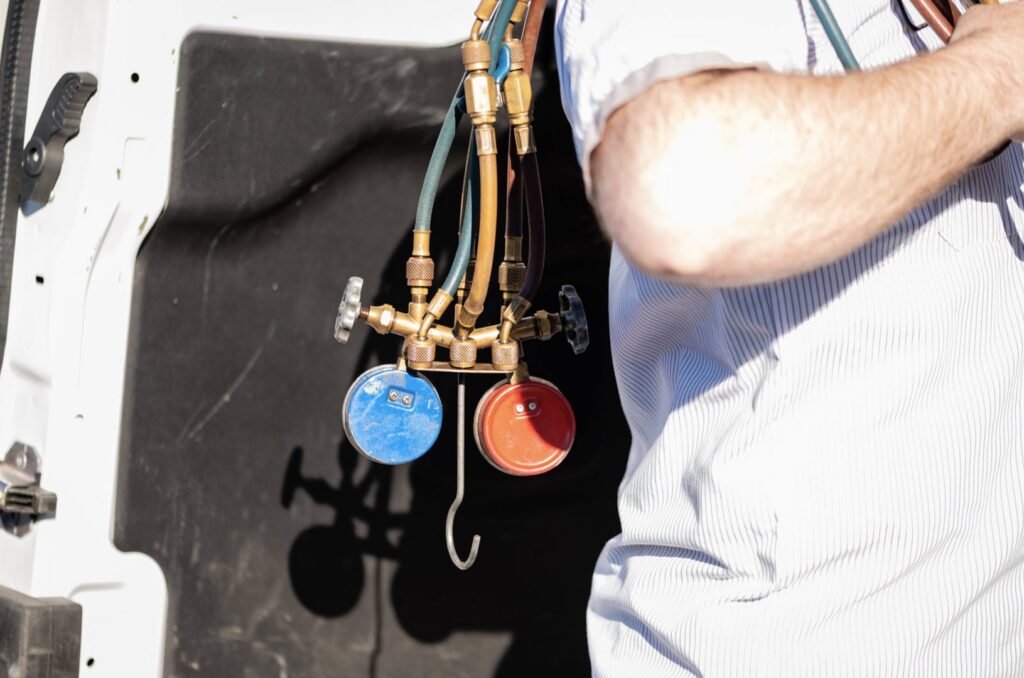 A close-up of an HVAC technician from DFH Company Heating and Air Conditioning holding refrigerant gauges in Louisville, KY