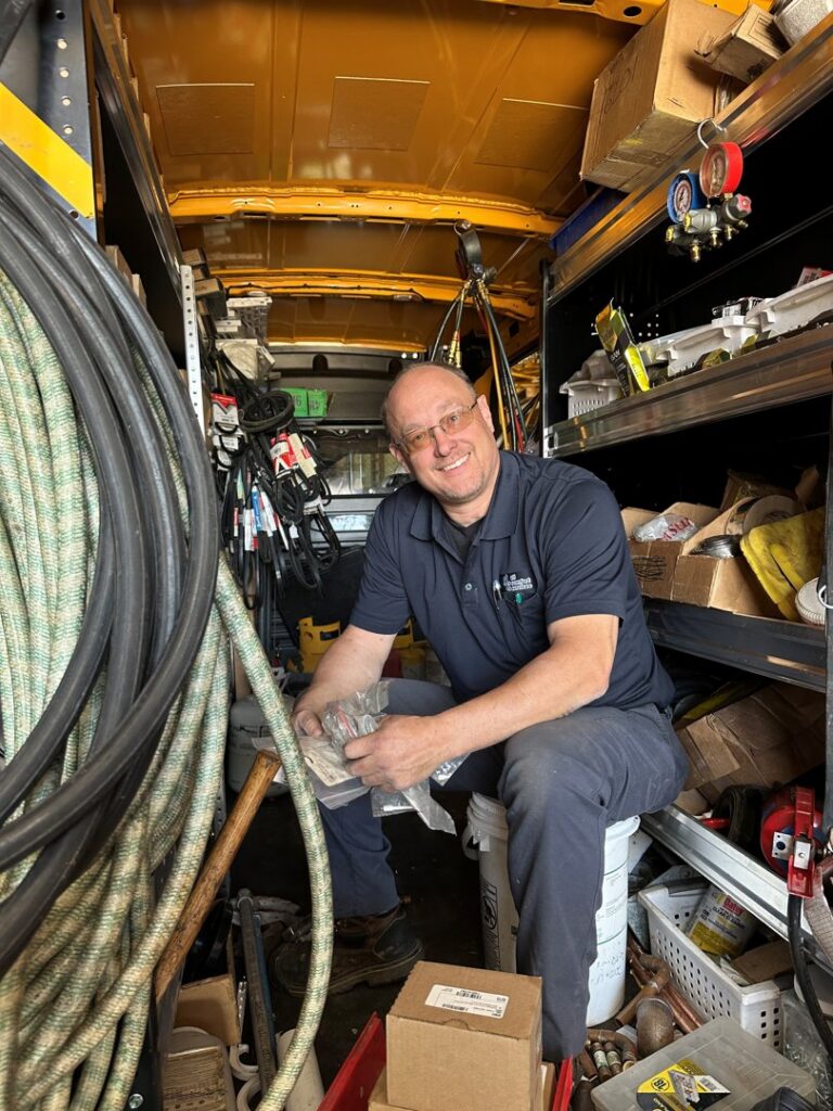 An HVAC technician sitting inside a well-stocked service van, ready for a job with All Comfort Services in Madison, WI