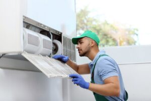 An HVAC technician inspecting an air conditioner filter for Baker Heating & Cooling in Dayton, OH.