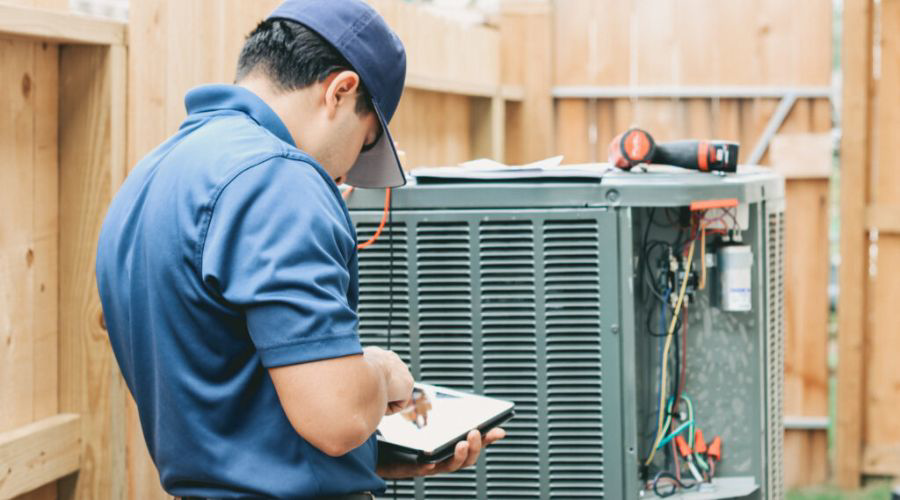 An HVAC technician inspecting an outdoor AC unit for Hibdon's Heat and Air in Oklahoma City, OK.