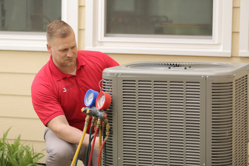 A Service Legends HVAC technician inspecting an outdoor AC unit with gauges in Des Moines, IA.