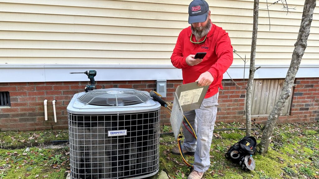 An HVAC technician inspecting an outdoor air conditioning unit with tools for Stoudenmire Heating & Air Conditioning in Columbia, SC.