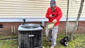 An HVAC technician inspecting an outdoor air conditioning unit with tools for Stoudenmire Heating & Air Conditioning in Columbia, SC.