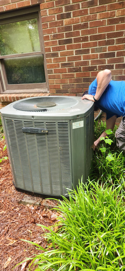 An HVAC technician inspecting an outdoor air conditioning unit at a residential property for Whittington HVAC in King, NC.