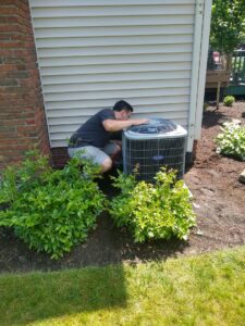 An HVAC technician from Wyles Heating & Air Conditioning Inc. inspecting an outdoor air conditioning unit in North Canton, OH.