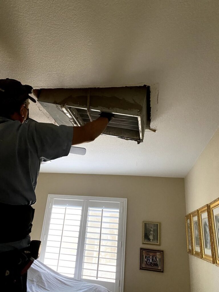An HVAC technician inspecting an air vent in a ceiling for Rebel Refrigeration in Las Vegas, NV.