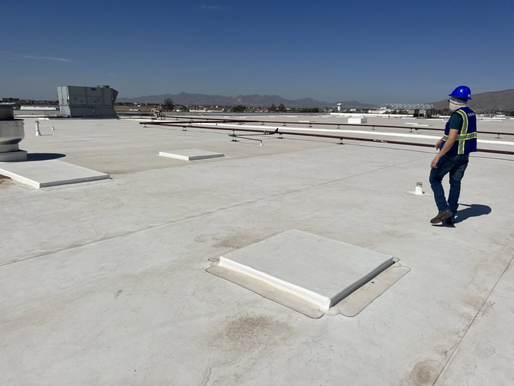 An HVAC technician inspecting a large commercial rooftop, likely for maintenance or installation by Anchor Air in El Paso, TX