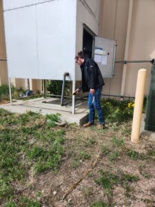 An HVAC technician inspecting an outdoor commercial unit during service by High Standard HVAC LLC in Cheyenne, WY.