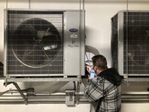 An HVAC technician inspecting a commercial indoor unit and taking a photo for Hurn Mechanical Heating & Cooling in El Cajon, CA.