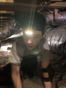 An HVAC technician inspecting ductwork in a crawl space for Workman Mechanical in Graham, NC.