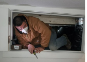 An HVAC technician inspecting ductwork in a confined space for KAP'S HVAC in Portland, OR.