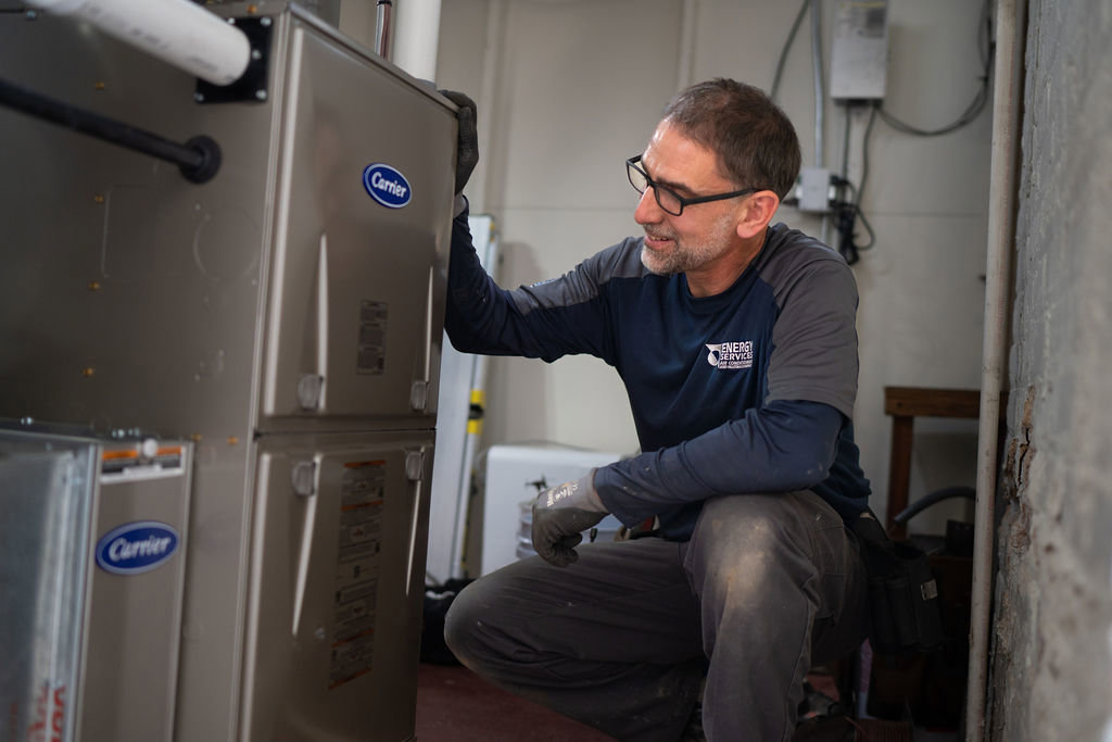 An HVAC technician inspecting a Carrier furnace or air handler for Alan Energy Services in Naperville, IL