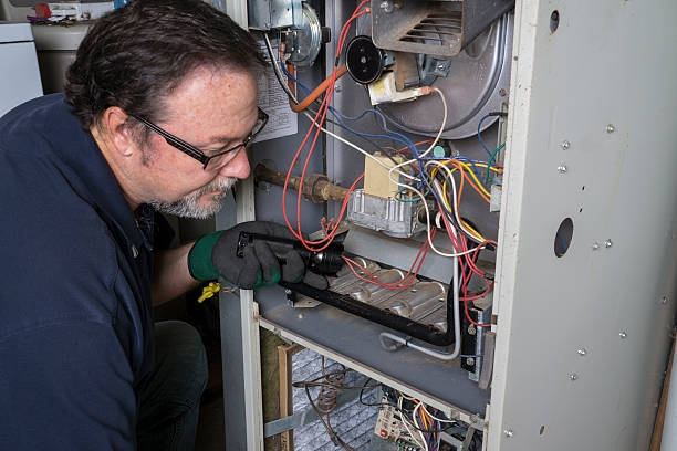 An HVAC technician inspecting the internal components of a furnace for Cleveland Air Comfort in Solon, OH.