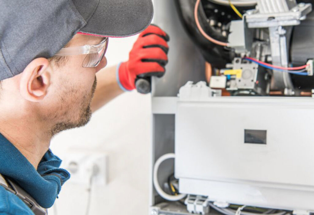 An HVAC technician inspecting the internal components of a furnace or boiler for Baker Heating & Cooling in Dayton, OH.