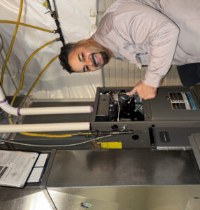 An HVAC technician inspecting a furnace during a service call for Inspired Heating & Cooling, Electric, Roofing, Repair LLC in Columbus, OH.