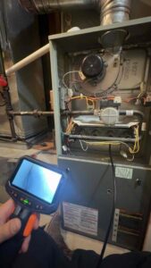 An HVAC technician using an inspection camera to examine the interior of a furnace for Markool Heating Cooling Plumbing in Frederick, MD.