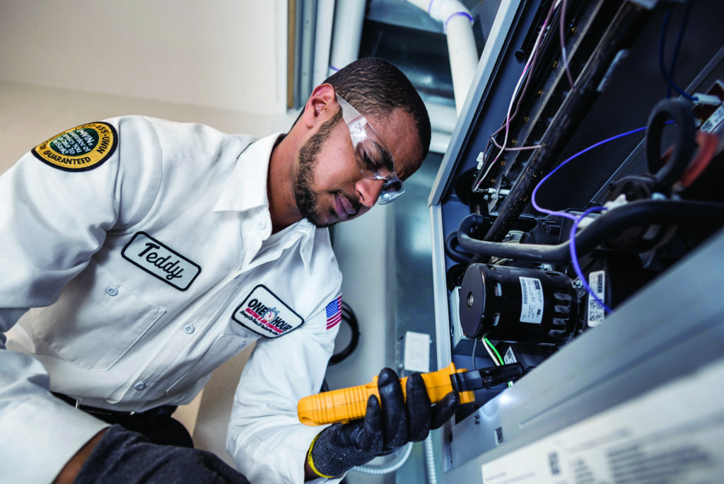 An HVAC technician inspecting an indoor furnace or air handler at One Hour Heating & Air Conditioning of Albany in Albany, NY