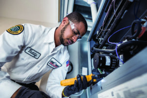 An HVAC technician inspecting an indoor furnace or air handler at One Hour Heating & Air Conditioning of Albany in Albany, NY